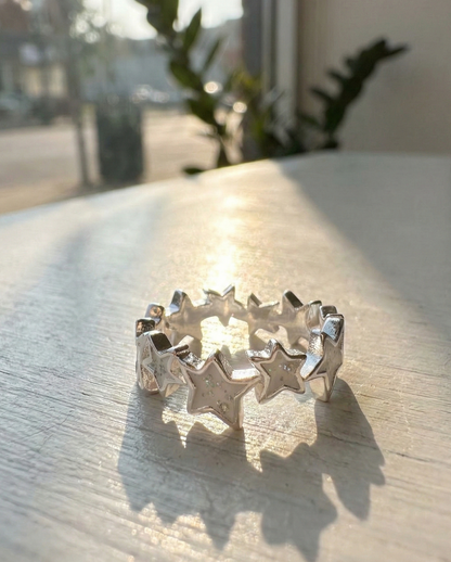 Top view of white enamel star ring with glitter particles catching natural sunlight