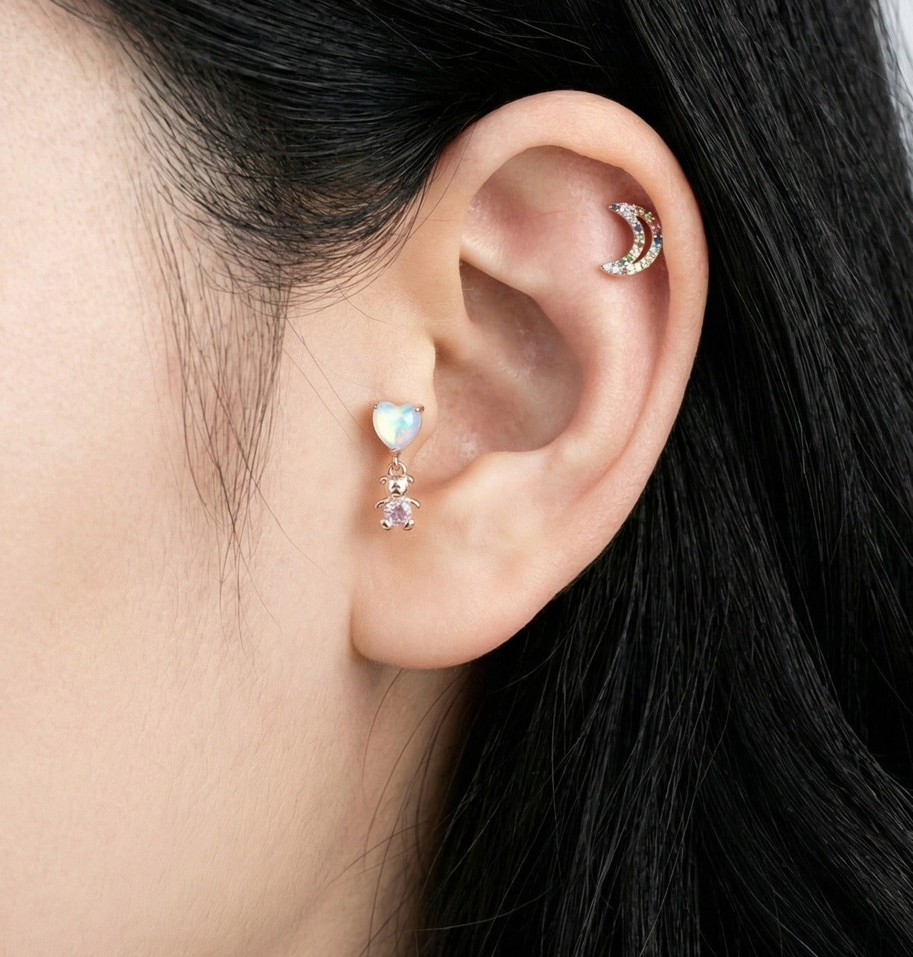 Aurora heart and teddy bear barbell piercing worn on helix cartilage with layered ear jewelry