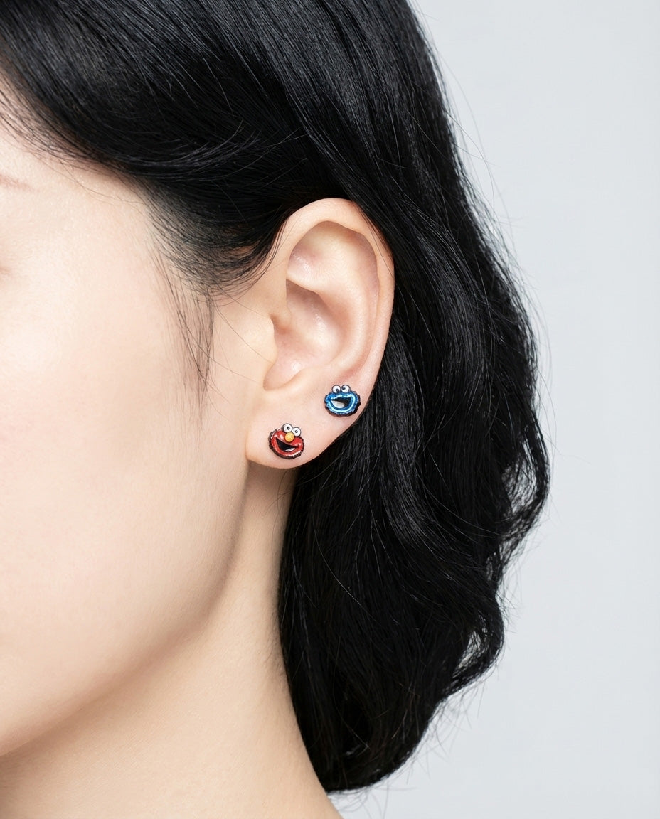 Side profile of model wearing Elmo and Cookie Monster character stud earrings on ear