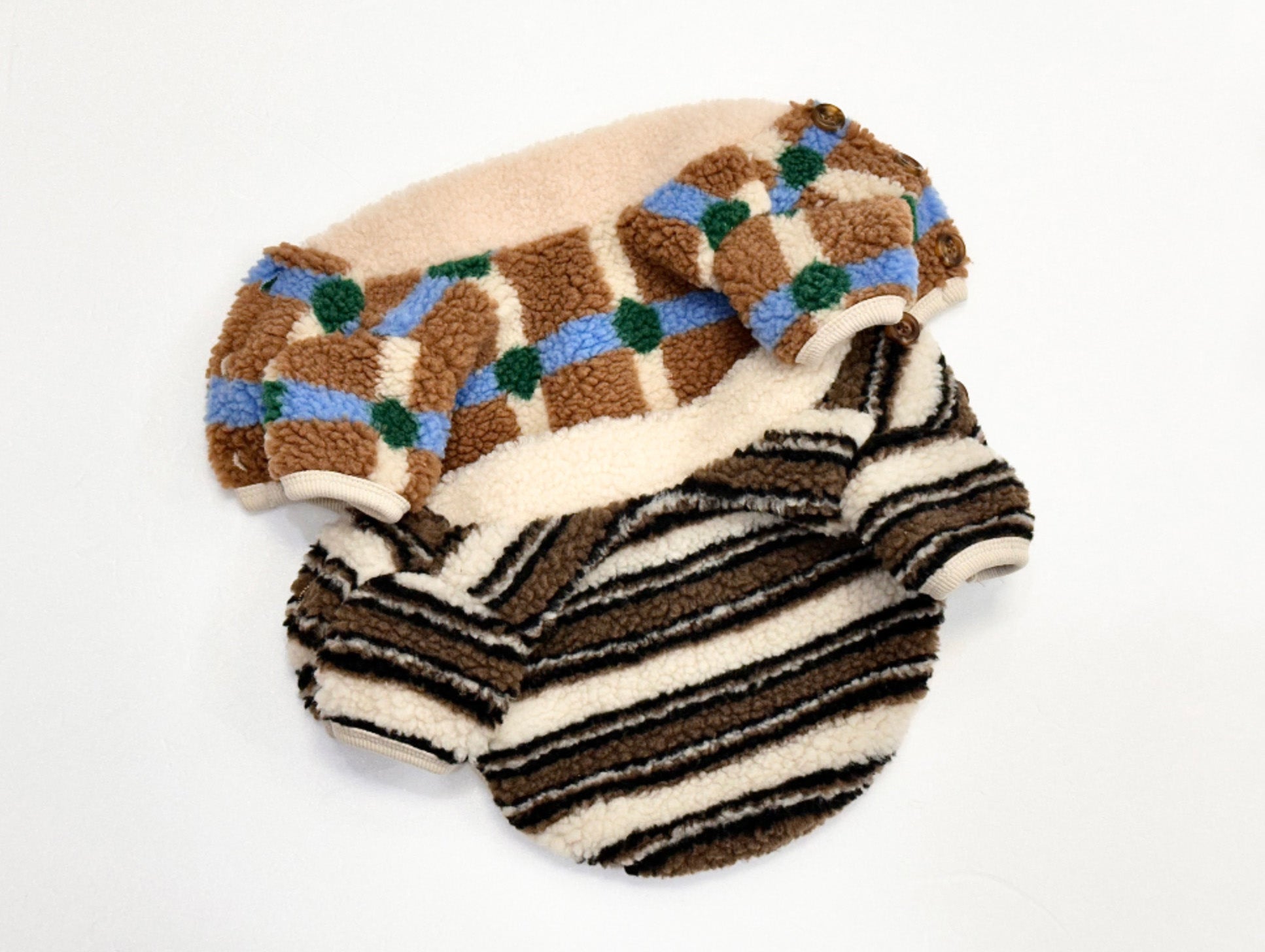 Flat lay of two sherpa fleece dog cardigans showing check and stripe patterns