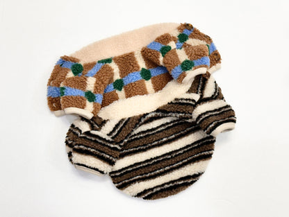 Flat lay of two sherpa fleece dog cardigans showing check and stripe patterns