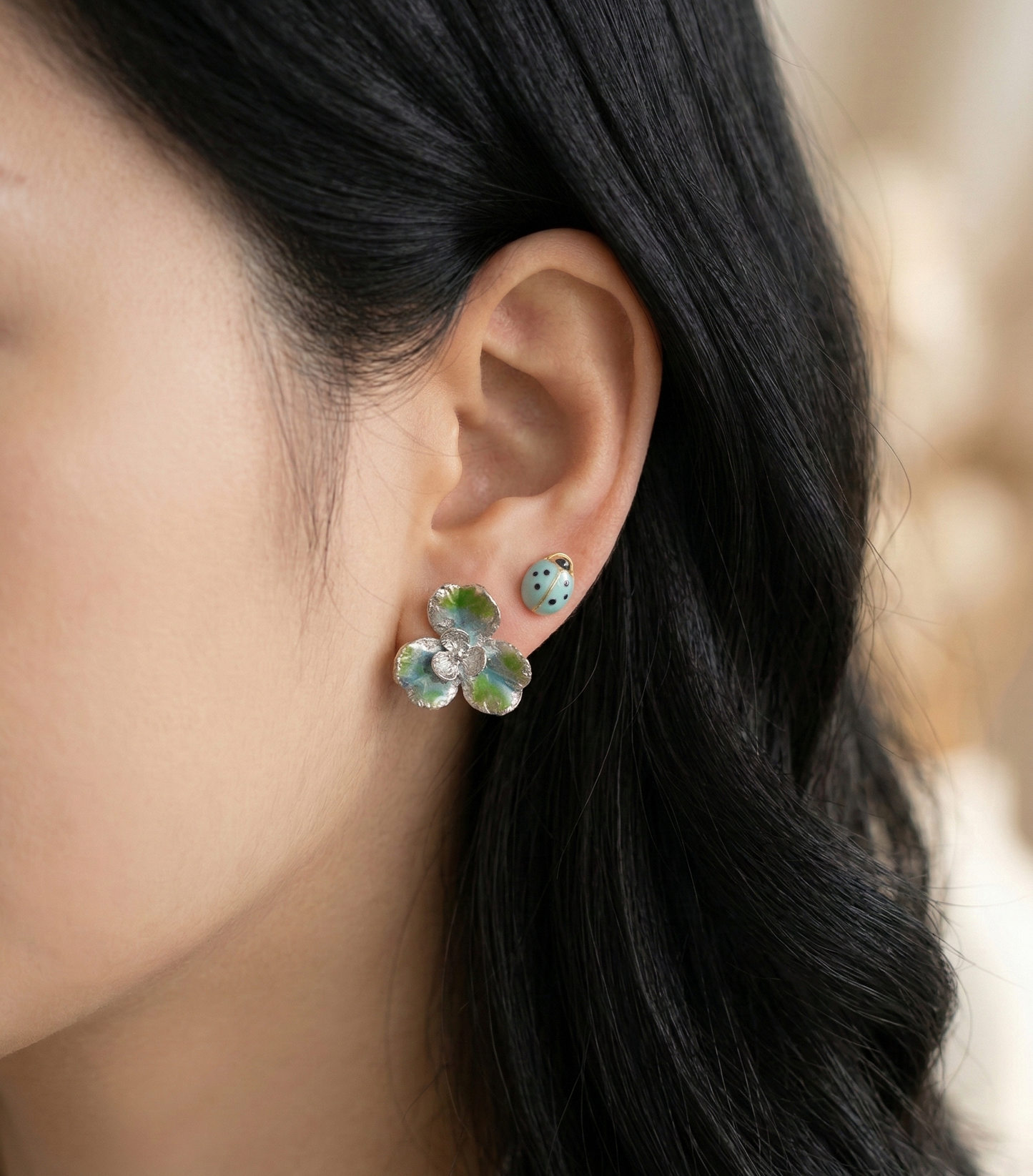  Close-up of a model wearing the Fresh Mint set, featuring a silver-blue clover and a mint ladybug stud earring.