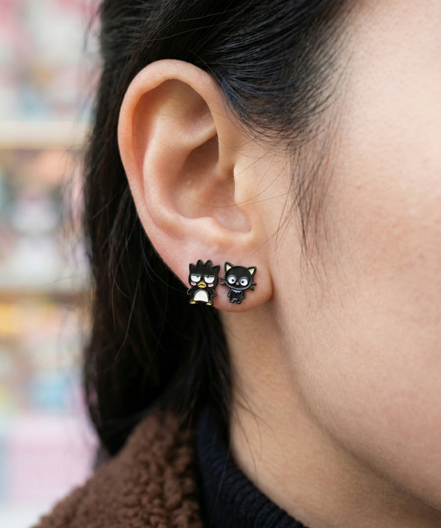 Close up ear shot of kawaii character earrings, showing glossy enamel finish and detailed facial features