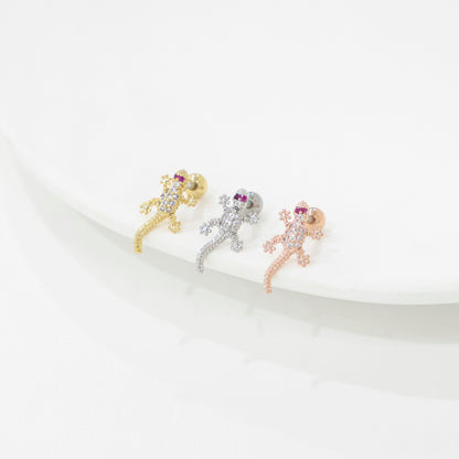 Three lizard-shaped earrings in gold, silver, and rose gold on a white surface.