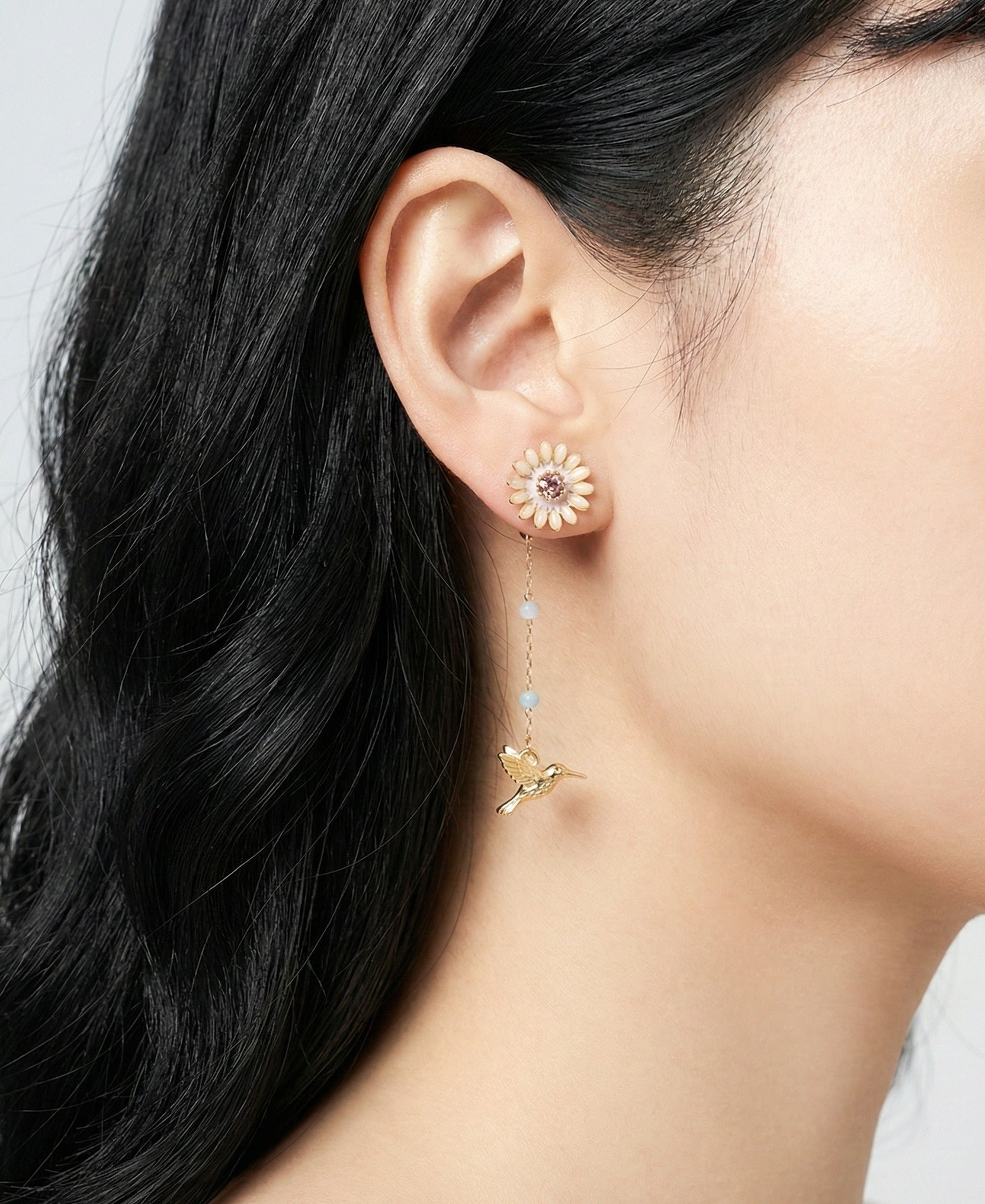 Model wearing gold daisy hummingbird earrings showing front-back design