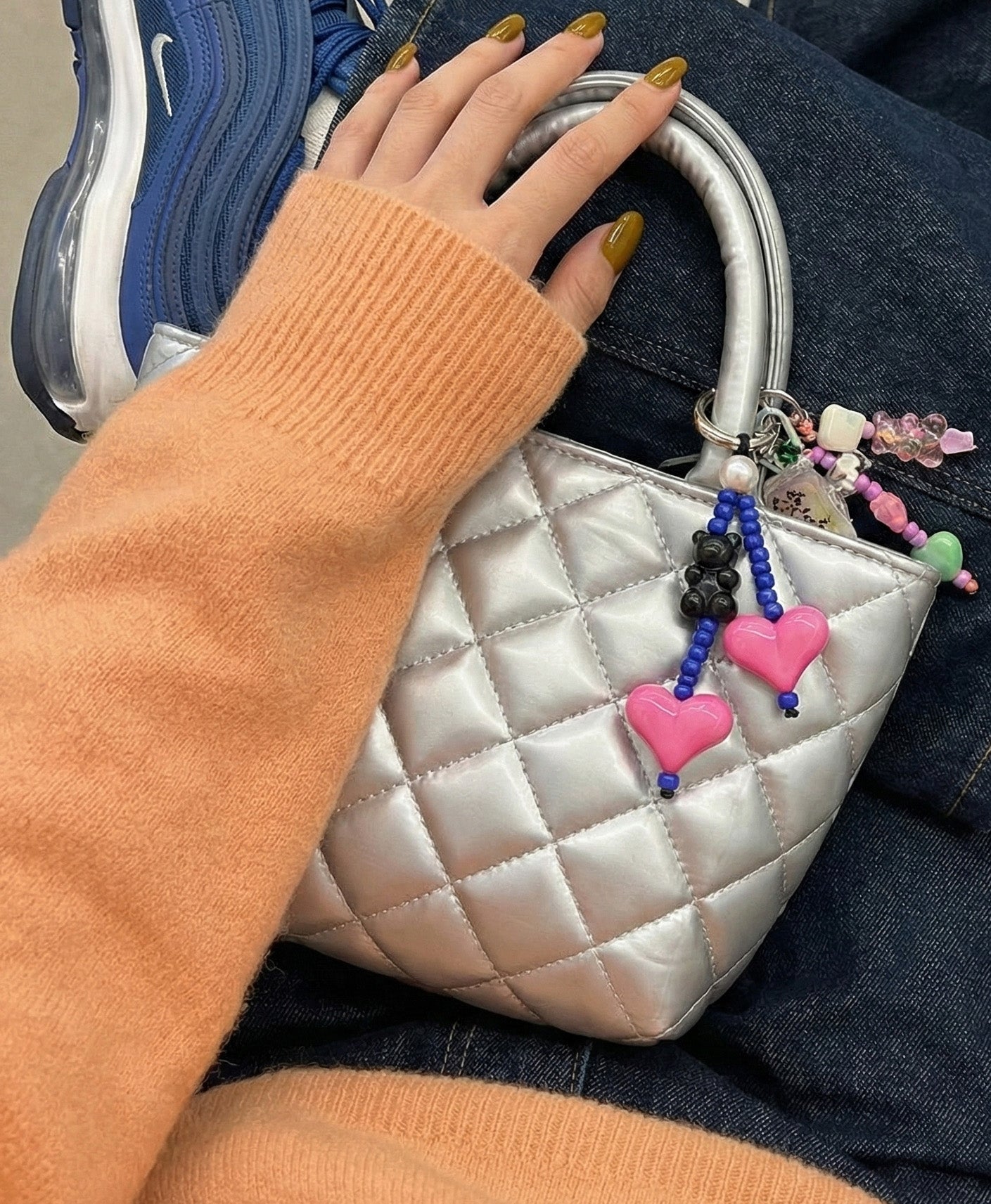 Pink and blue heart beaded bag charm with pearl accent on silver quilted bag with mustard sweater