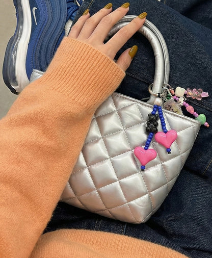 Pink and blue heart beaded bag charm with pearl accent on silver quilted bag with mustard sweater
