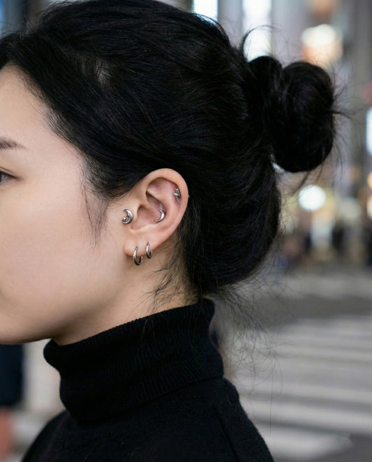 Side view of layered surgical steel moon and lightning bolt cartilage piercings