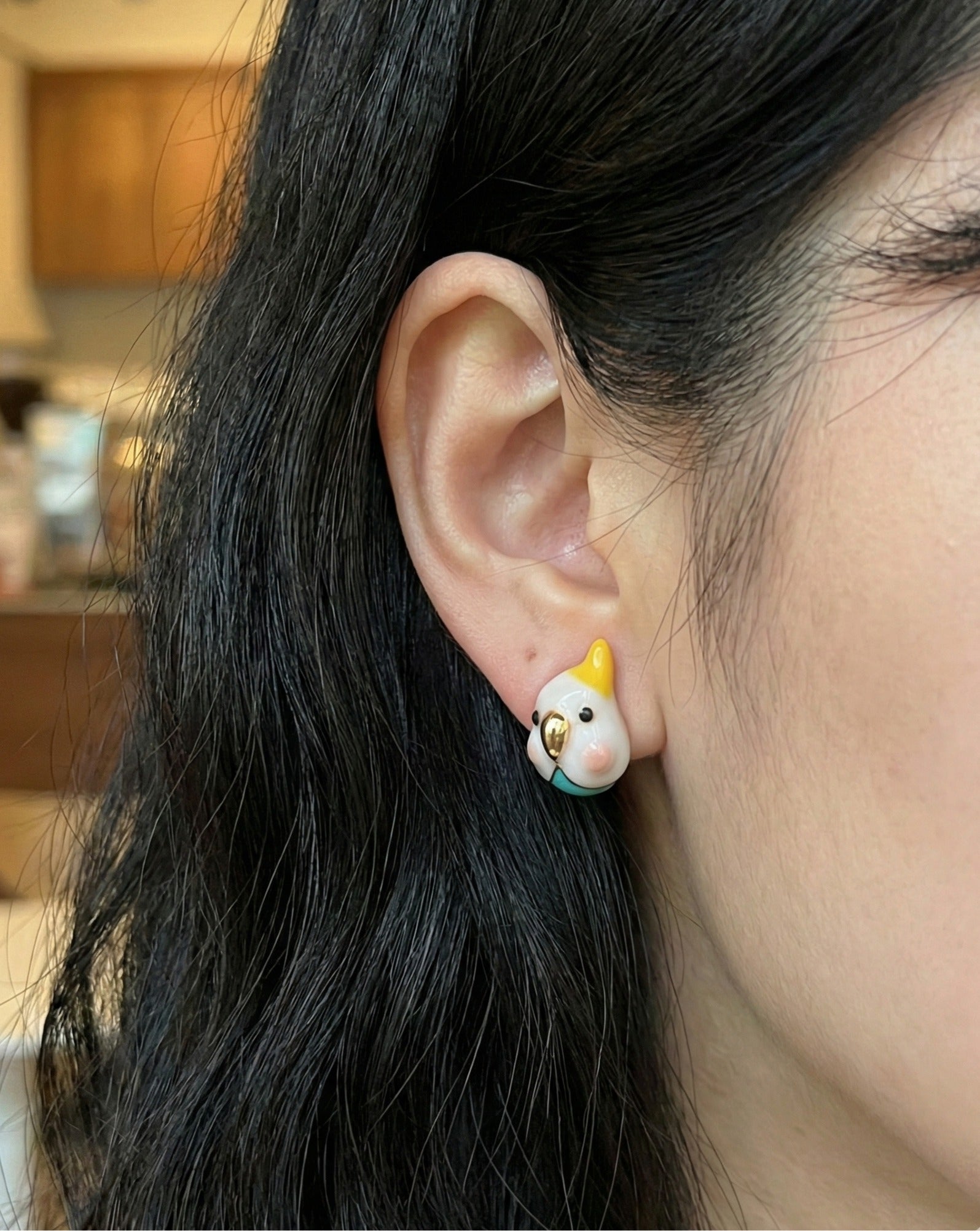 Model wearing cockatiel stud earring — white bird with yellow crest on ear