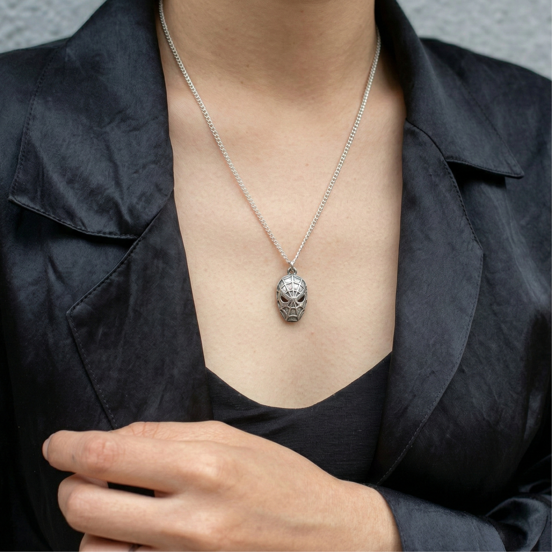 Woman wearing a unique silver spider pendant necklace with a black blazer
