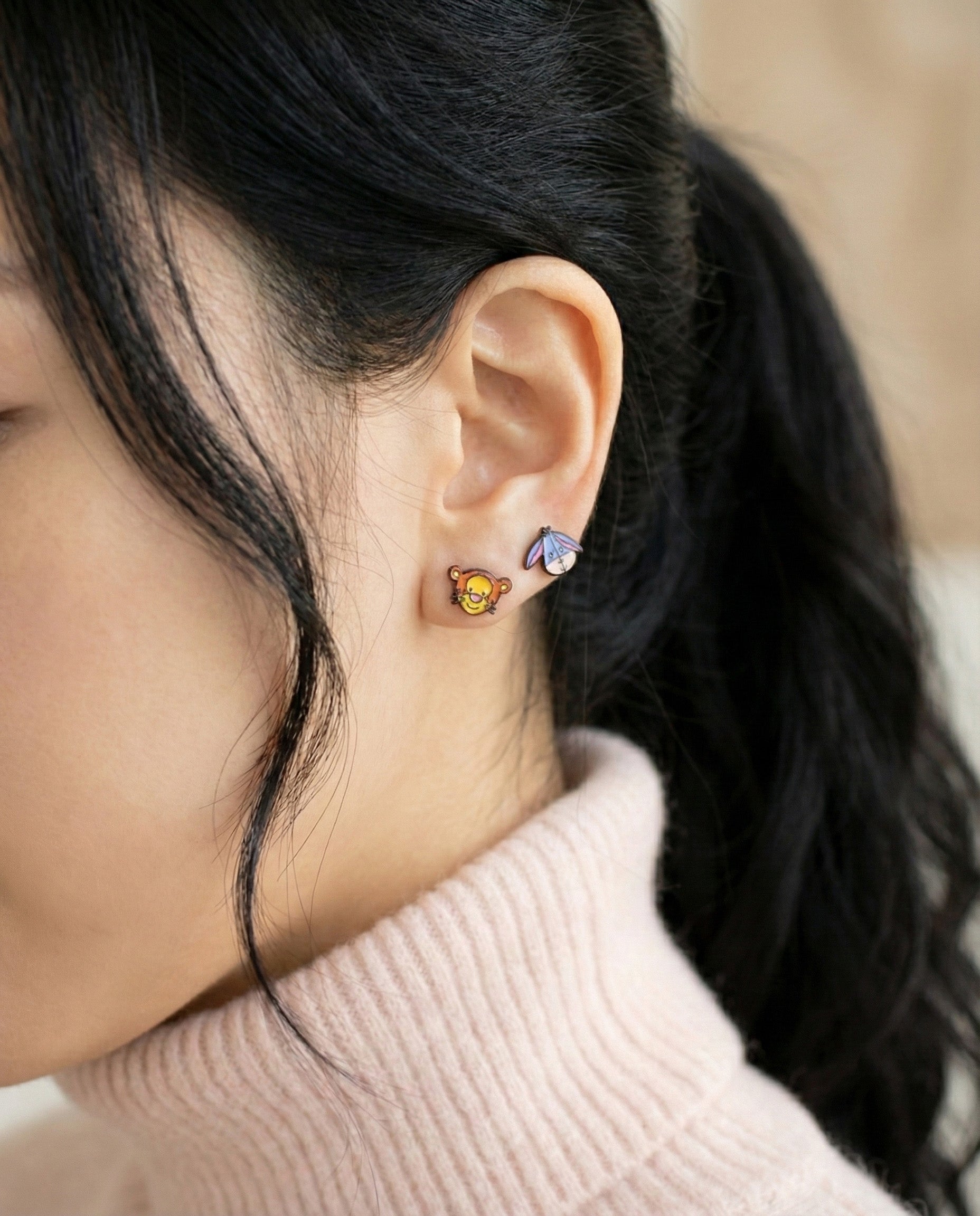 Tigger and Eeyore earrings layered on ear showcasing mix-and-match styling