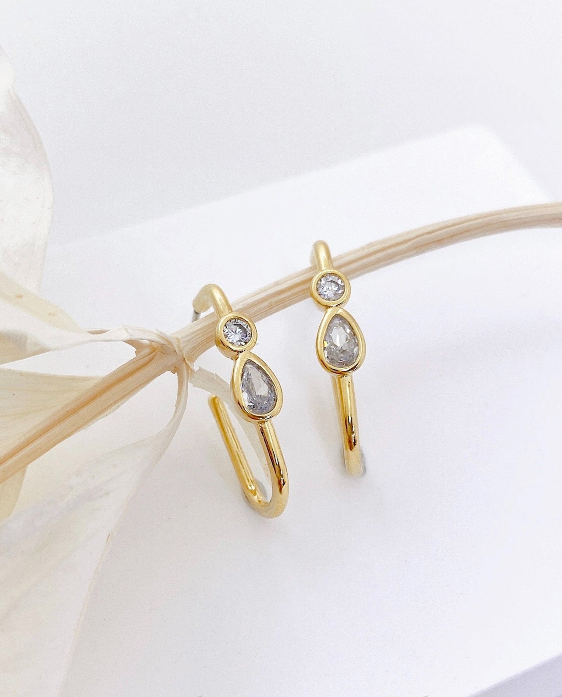 Close-up detail of gold bezel-set teardrop pear-cut and round CZ stones on brass hoop earring