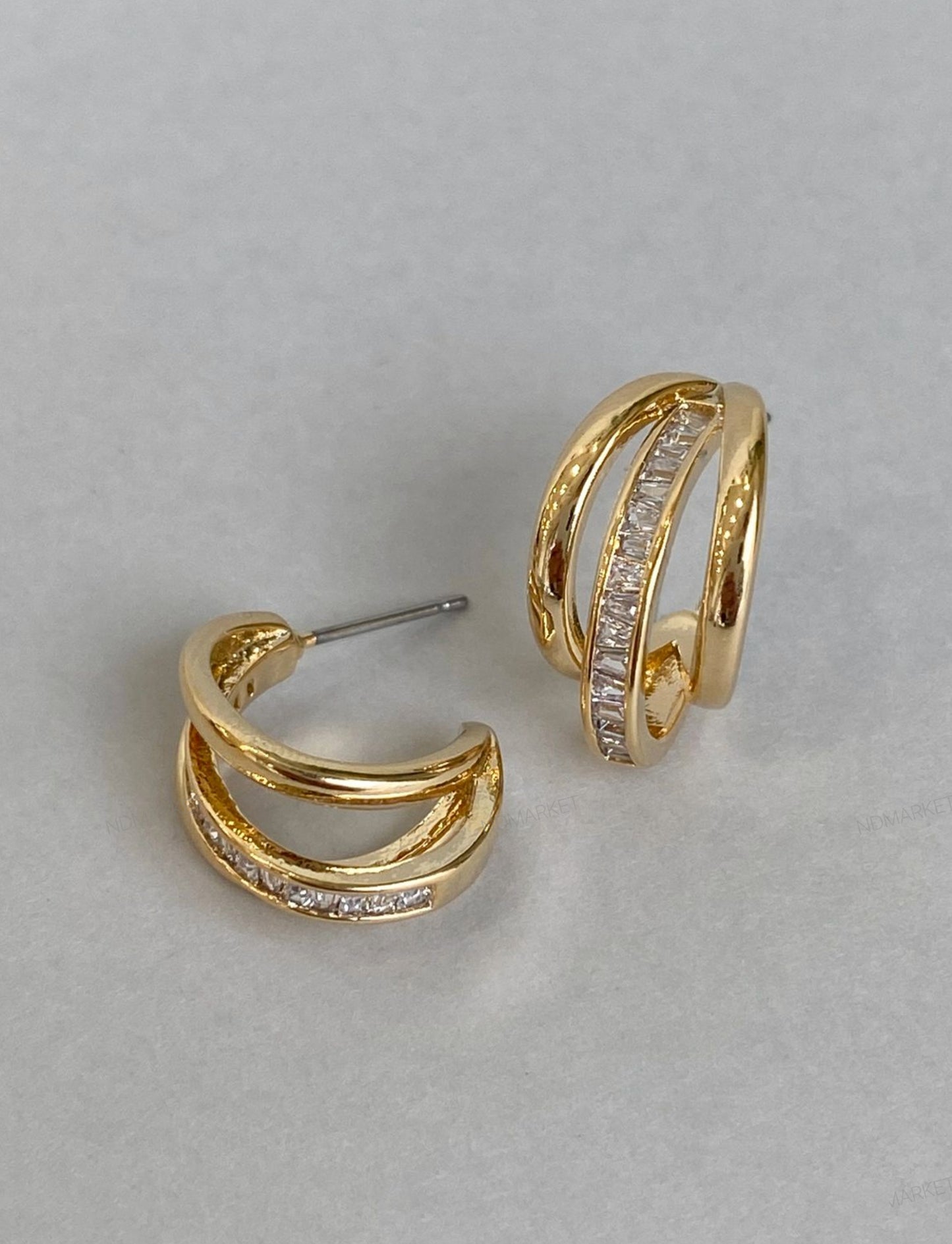 Flat lay of gold triple row baguette huggie earrings showing titanium posts