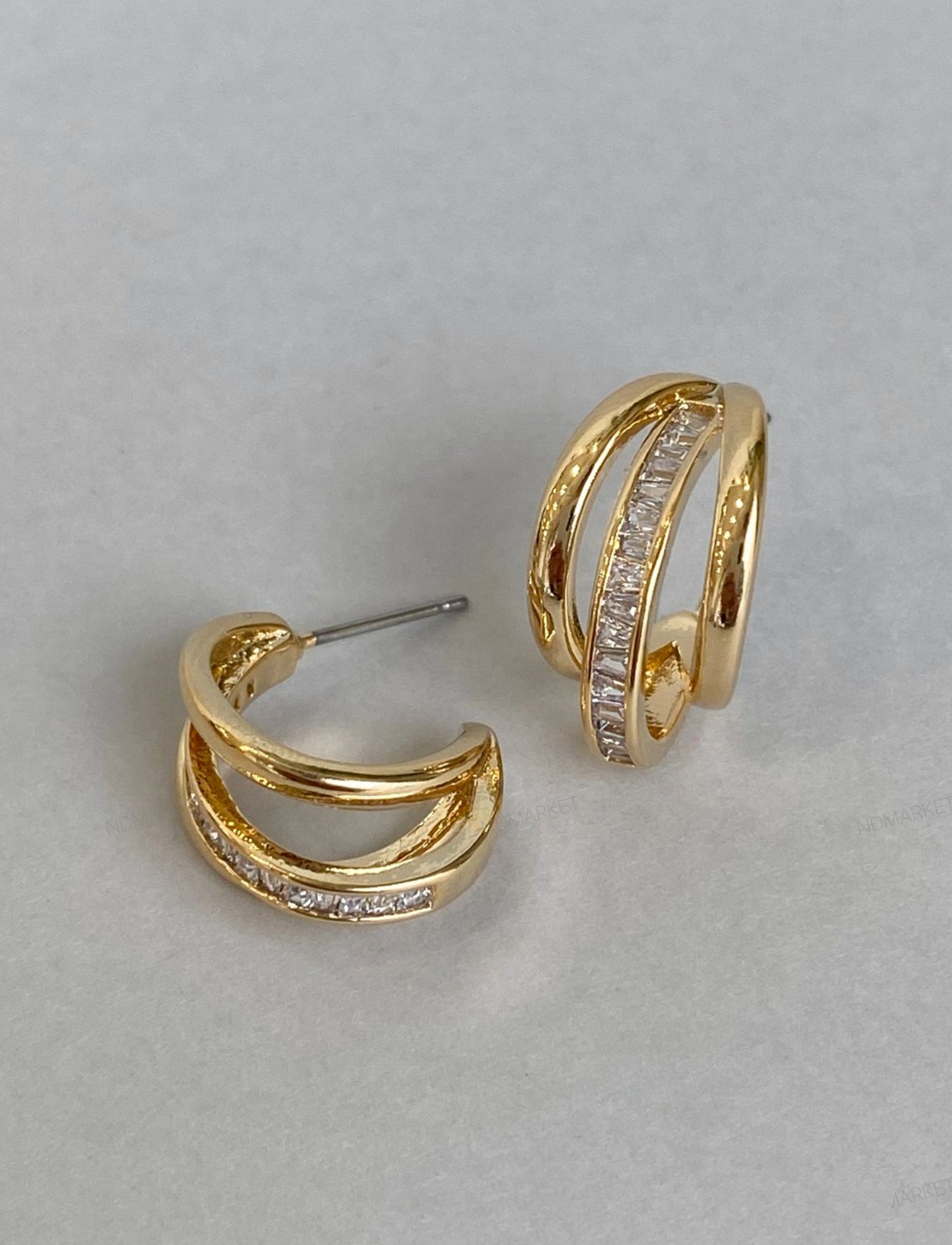 Flat lay of gold triple row baguette huggie earrings showing titanium posts