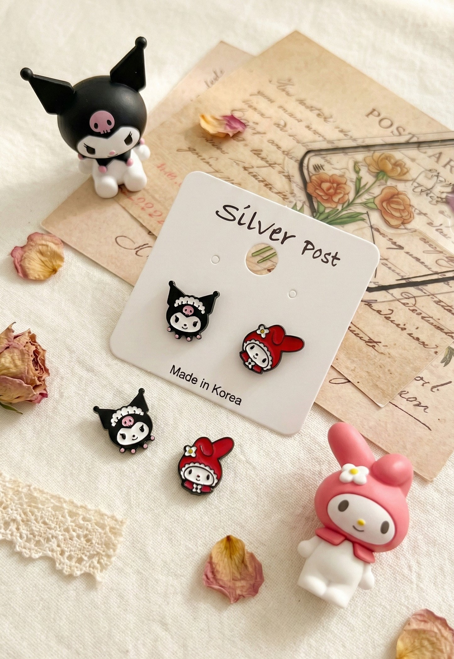 Detailed product shot of Kuromi and My Melody asymmetrical earring set on vintage letters