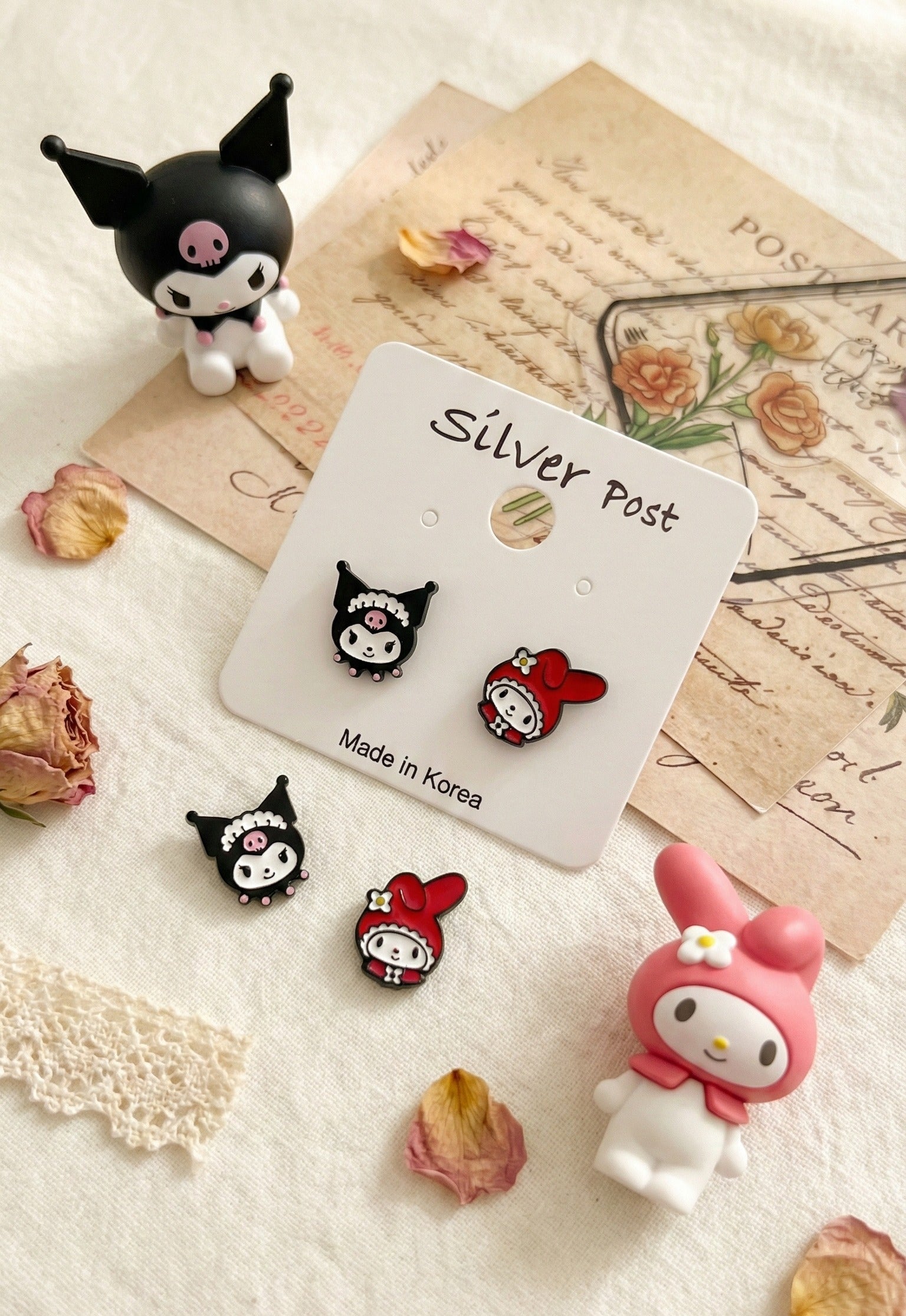 Detailed product shot of Kuromi and My Melody asymmetrical earring set on vintage letters