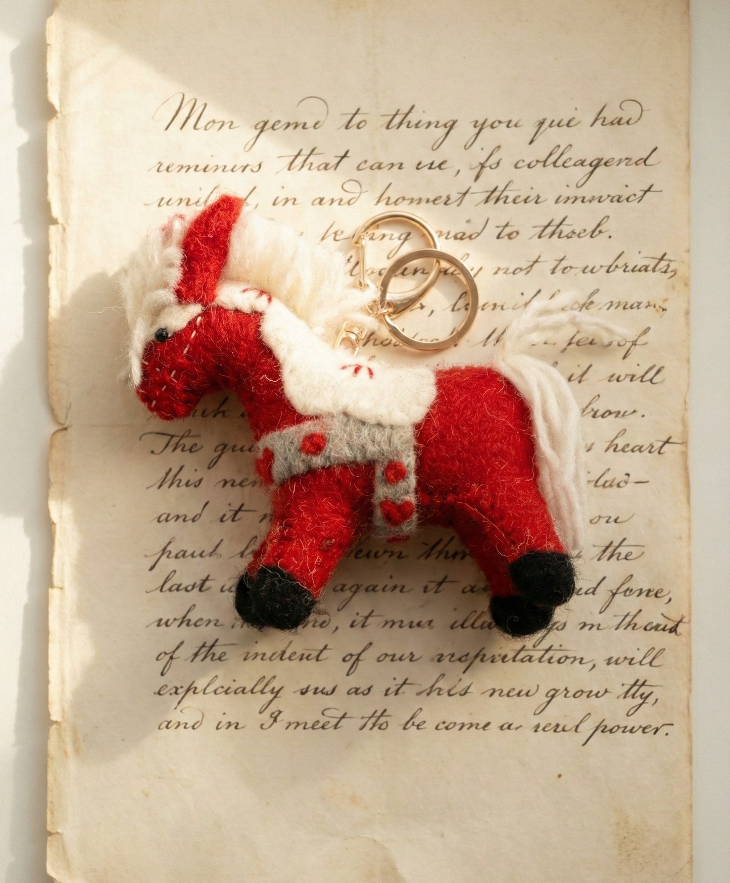 Flat lay of red felt horse keychain on vintage letter paper, cottagecore aesthetic styling for gift wrapping
