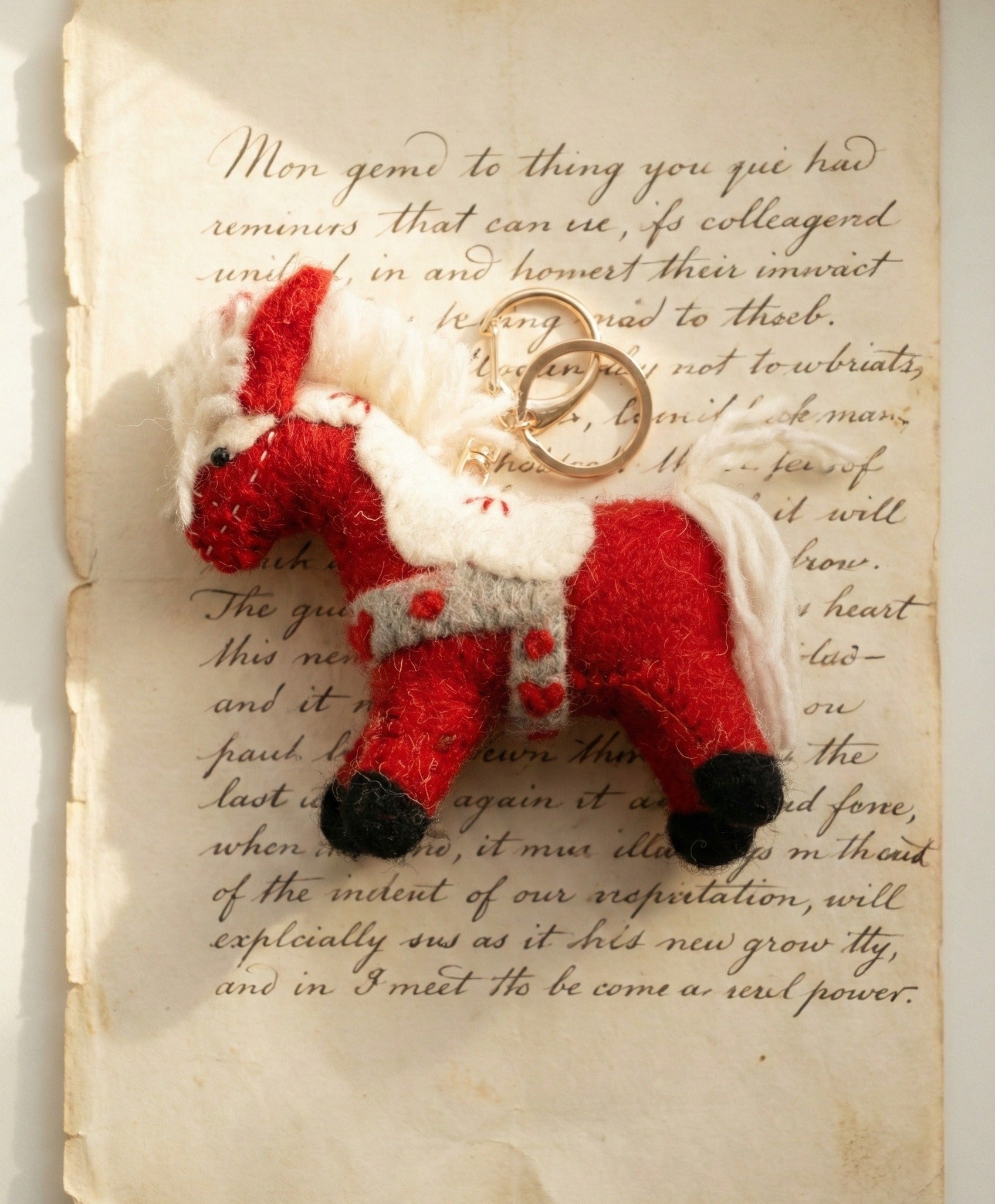 Flat lay of red felt horse keychain on vintage letter paper, cottagecore aesthetic styling for gift wrapping