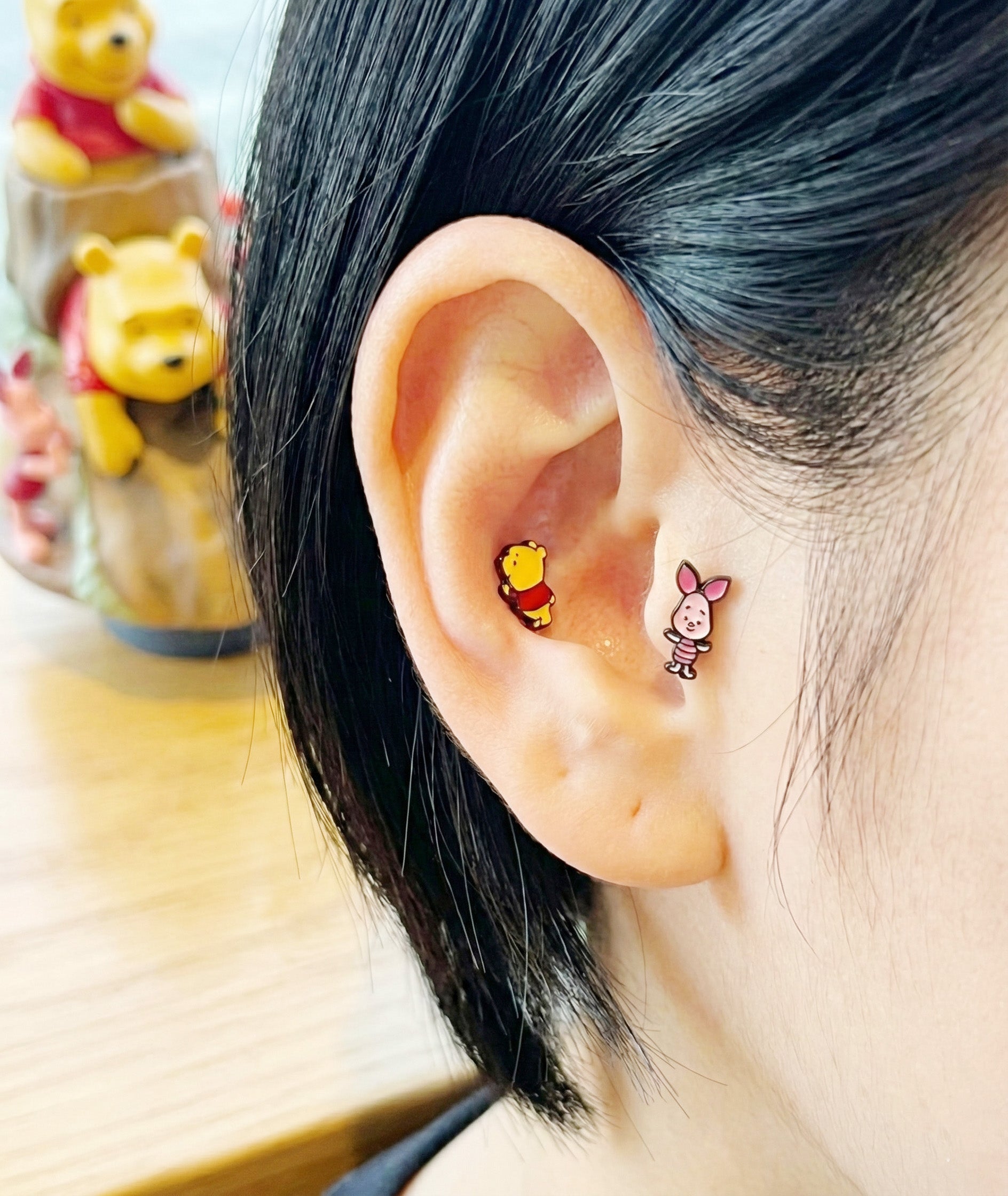 Winnie the Pooh and Piglet barbell studs worn in helix cartilage piercing