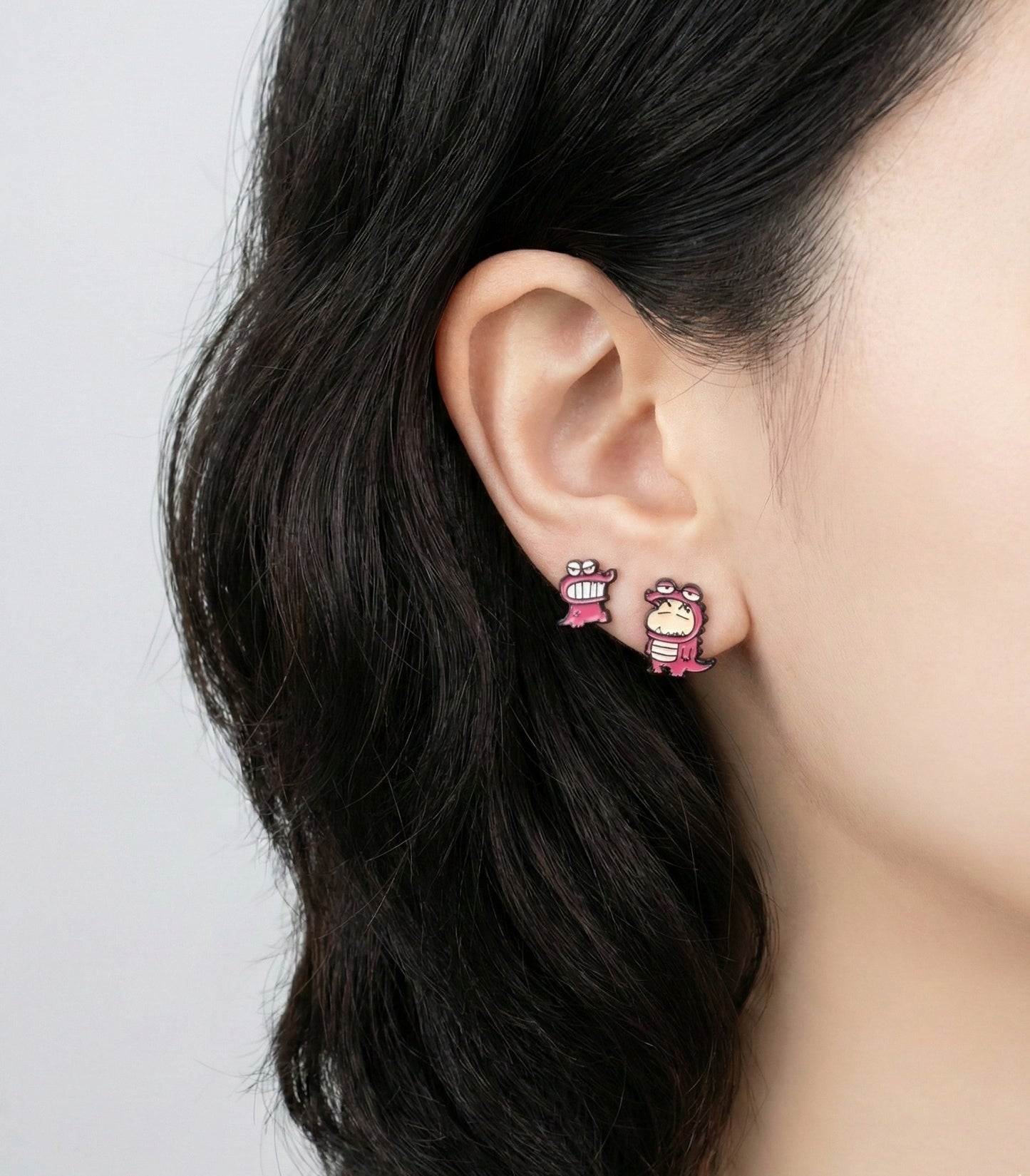 Side profile of model wearing pink Chocobi dinosaur and Shin-chan mismatched earrings with dark hair
