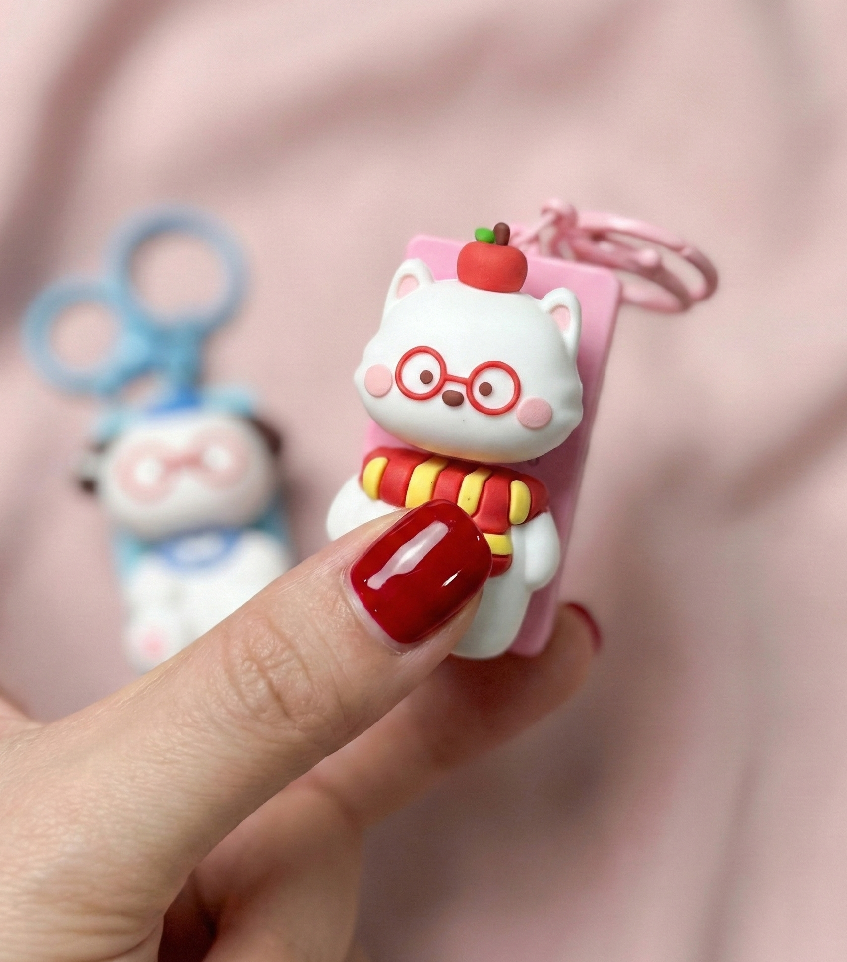 
Close-up of pink cat keycap keychain with red glasses and striped scarf