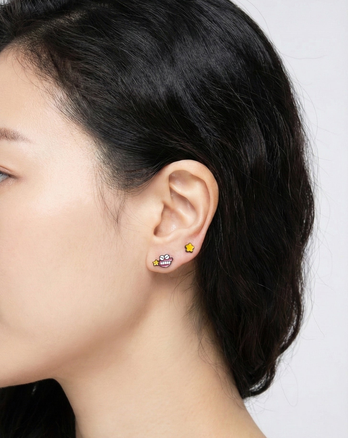 Chocobi character earring and yellow star stud worn together in curated ear piercing, layered earscape styling