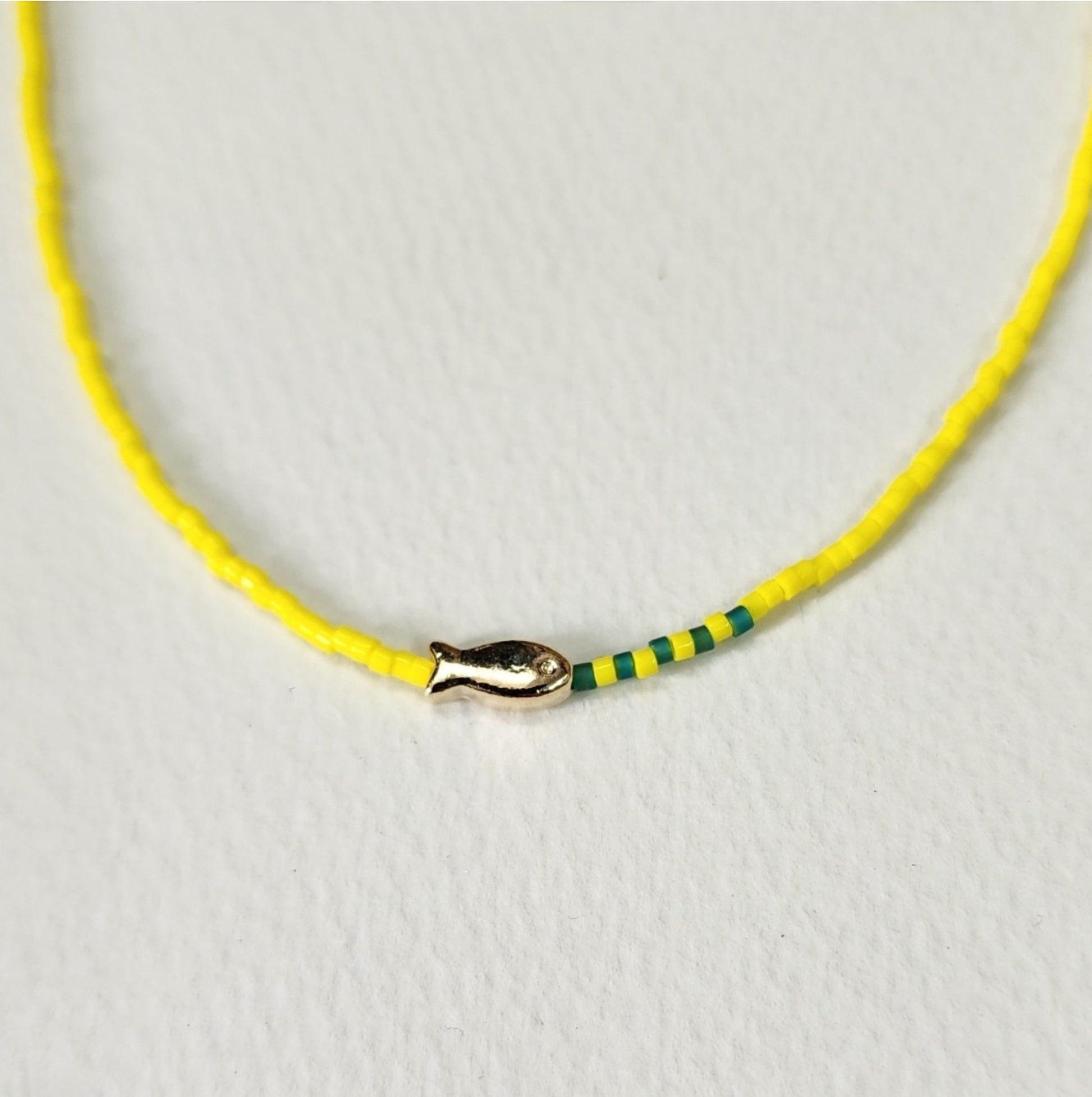 Lemon yellow seed bead choker featuring gold fish pendant and green accent beads detail shot