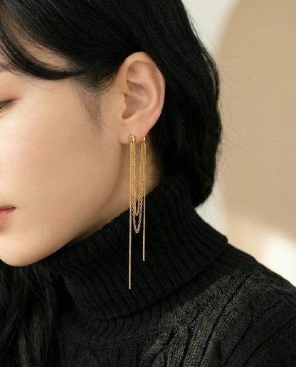 Close up of gold layered tassel chain earrings on model with black knit sweater