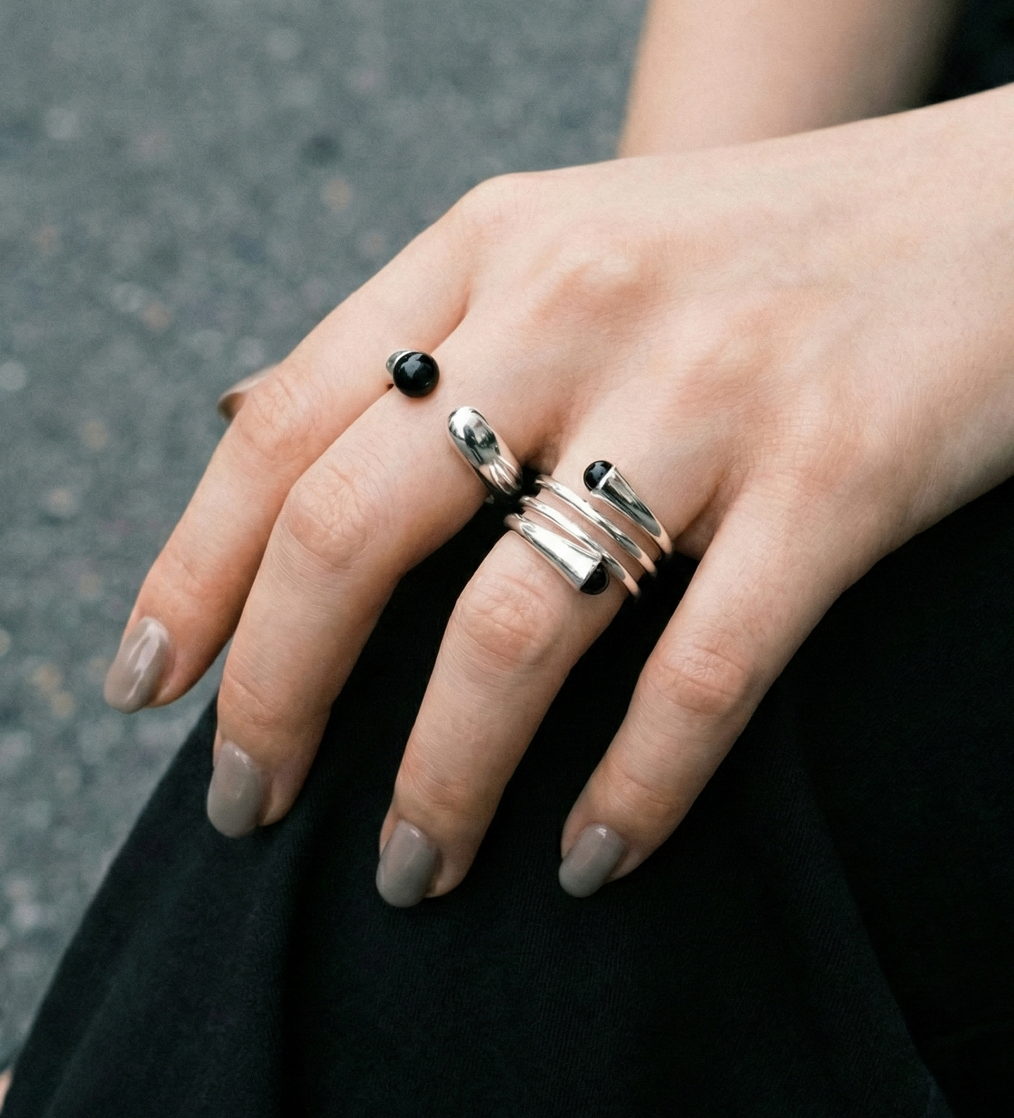 Outdoor lifestyle shot of model wearing black onyx sterling silver single and spiral rings on black outfit