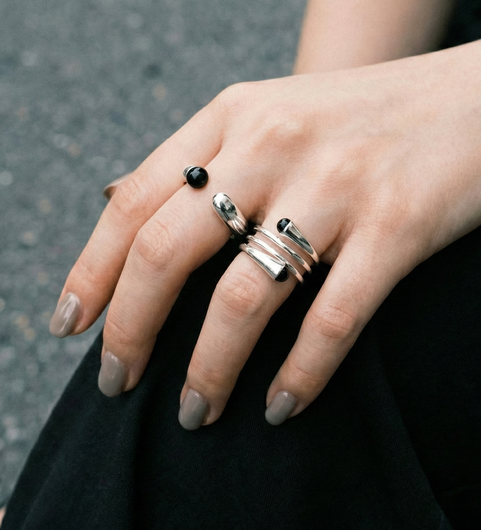 Outdoor lifestyle shot of model wearing black onyx sterling silver single and spiral rings on black outfit