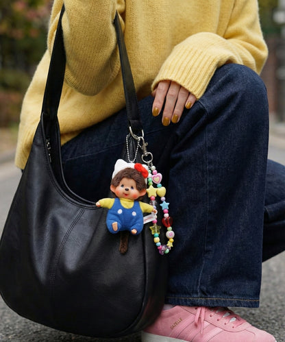 Black leather hobo bag with Monchhichi keychain and beaded accessories street style