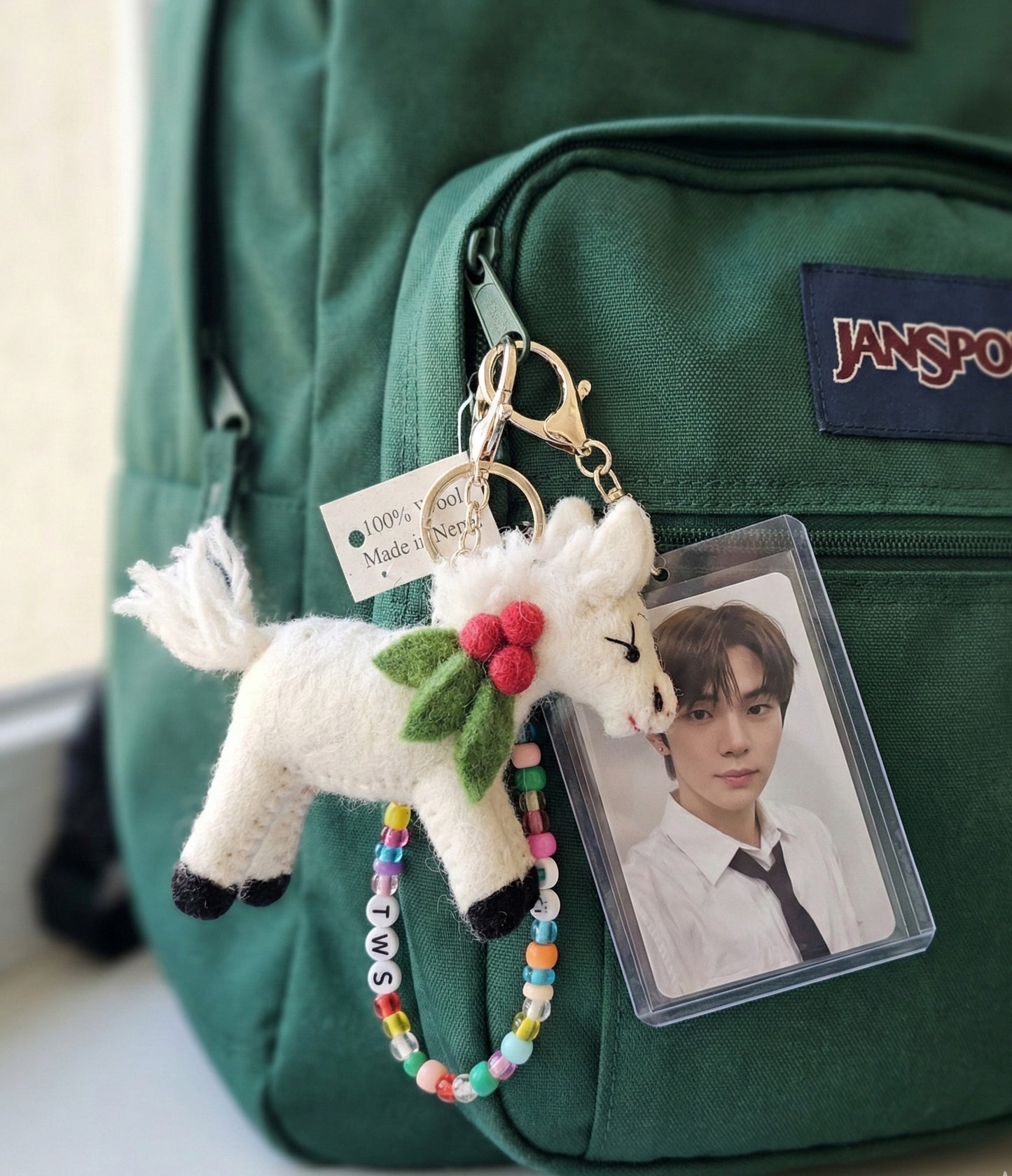 White felt horse bag charm on green JanSport backpack with colorful beaded name tag and photocard