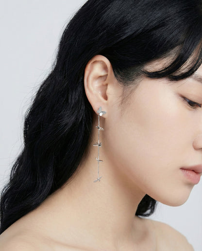 Silver butterfly long drop earrings worn by model side angle view
