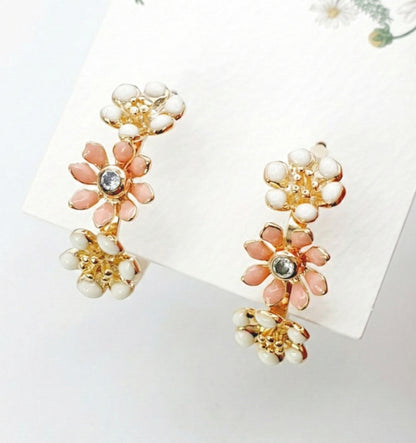Close-up of peach blossom gold tone enamel flower hoop earrings with white and peach petals