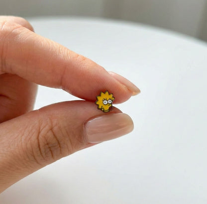 Mini Lisa Simpson character stud earring held in hand, yellow enamel with spiky hair detail visible