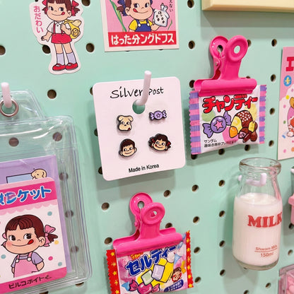 Peko Chan earring set displayed with retro Y2K aesthetic props including vintage Japanese candy packages and milk bottle on mint pegboard