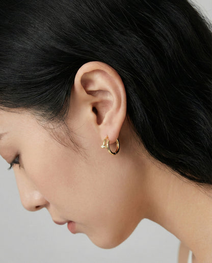 Tilted profile view of model wearing gold double hoop earrings.