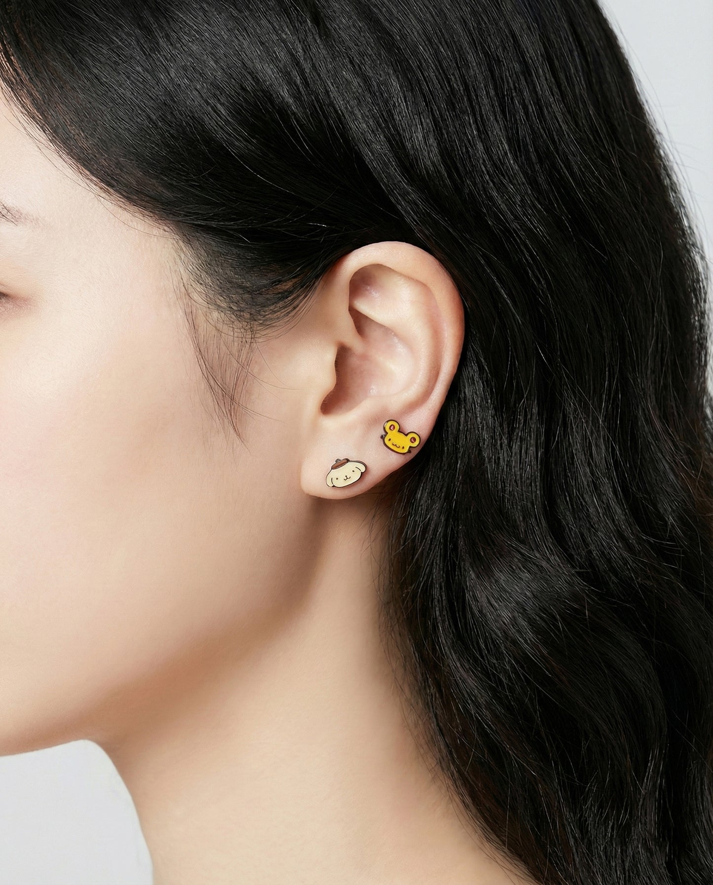 Pompompurin yellow character earrings with banana and flower enamel studs on ear