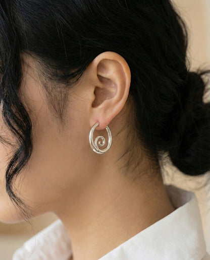 Silver sculptural hoop earrings close-up on model with hair up