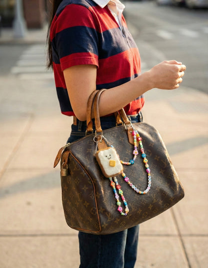 Handmade felt toast keychain attached to luxury designer bag with beaded strap charm