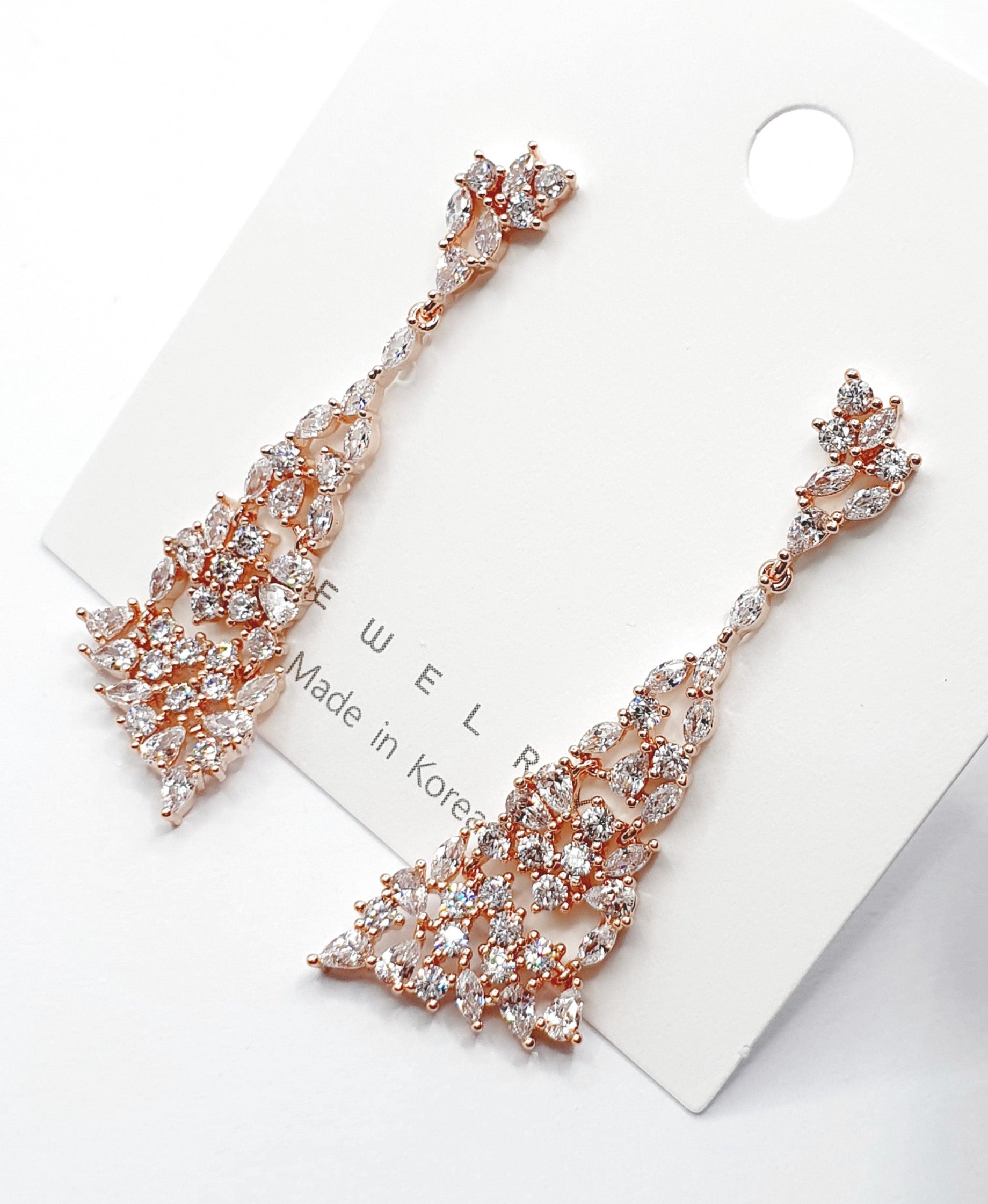 Flat lay of rose gold CZ chandelier earrings on white card