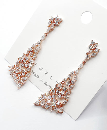 Flat lay of rose gold CZ chandelier earrings on white card