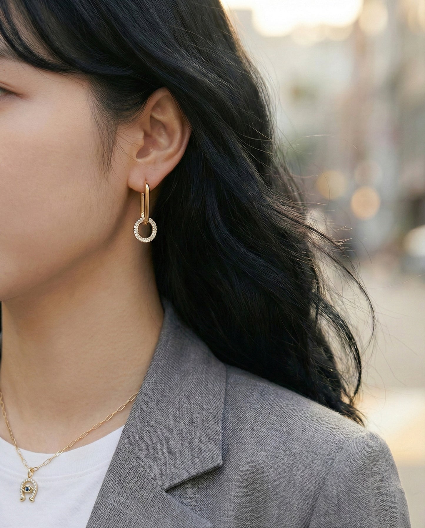 Gold oval link drop earrings worn with gray blazer and white tee, office look