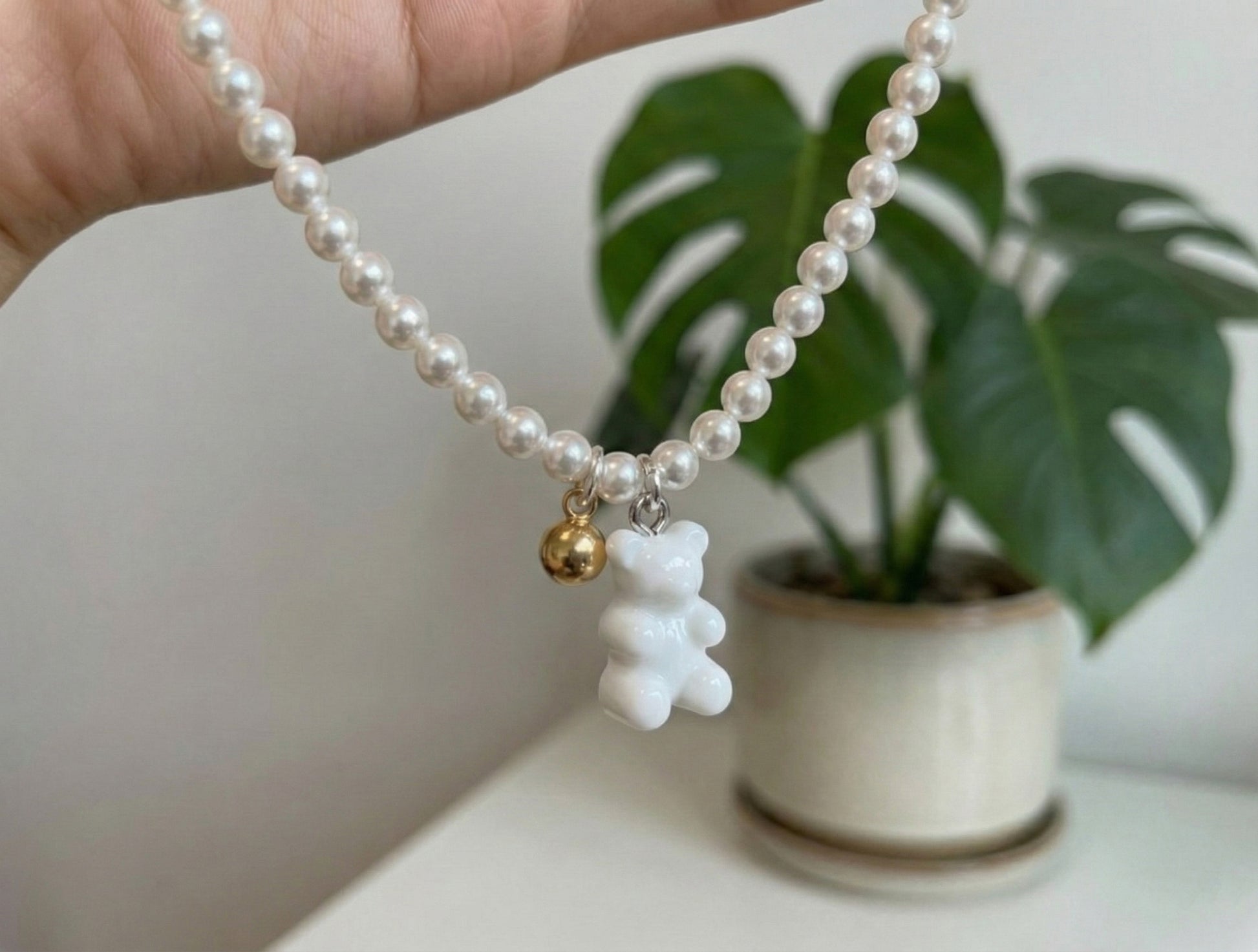White gummy bear charm with gold accent bead on Swarovski pearl necklace close-up