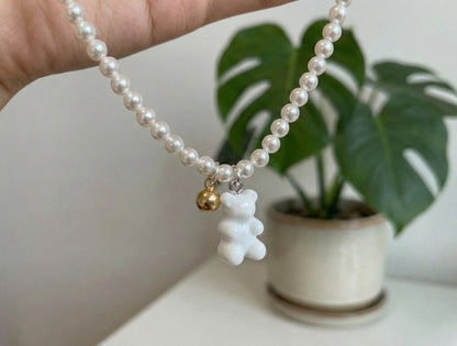 White gummy bear charm with gold accent bead on Swarovski pearl necklace close-up