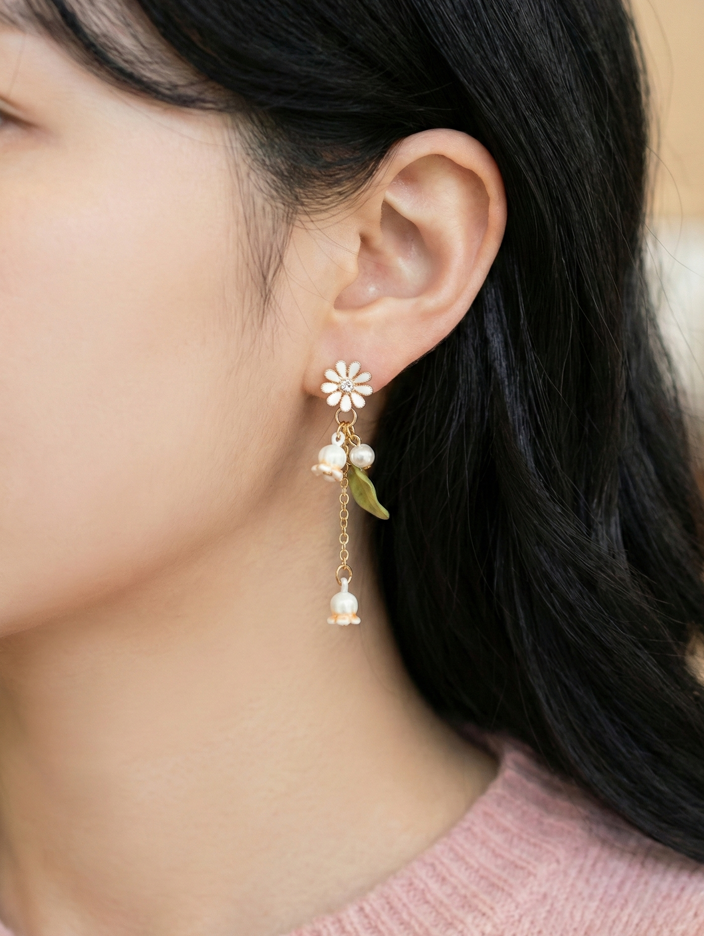 Woman modeling the white botanical drop earring with a green leaf detail.