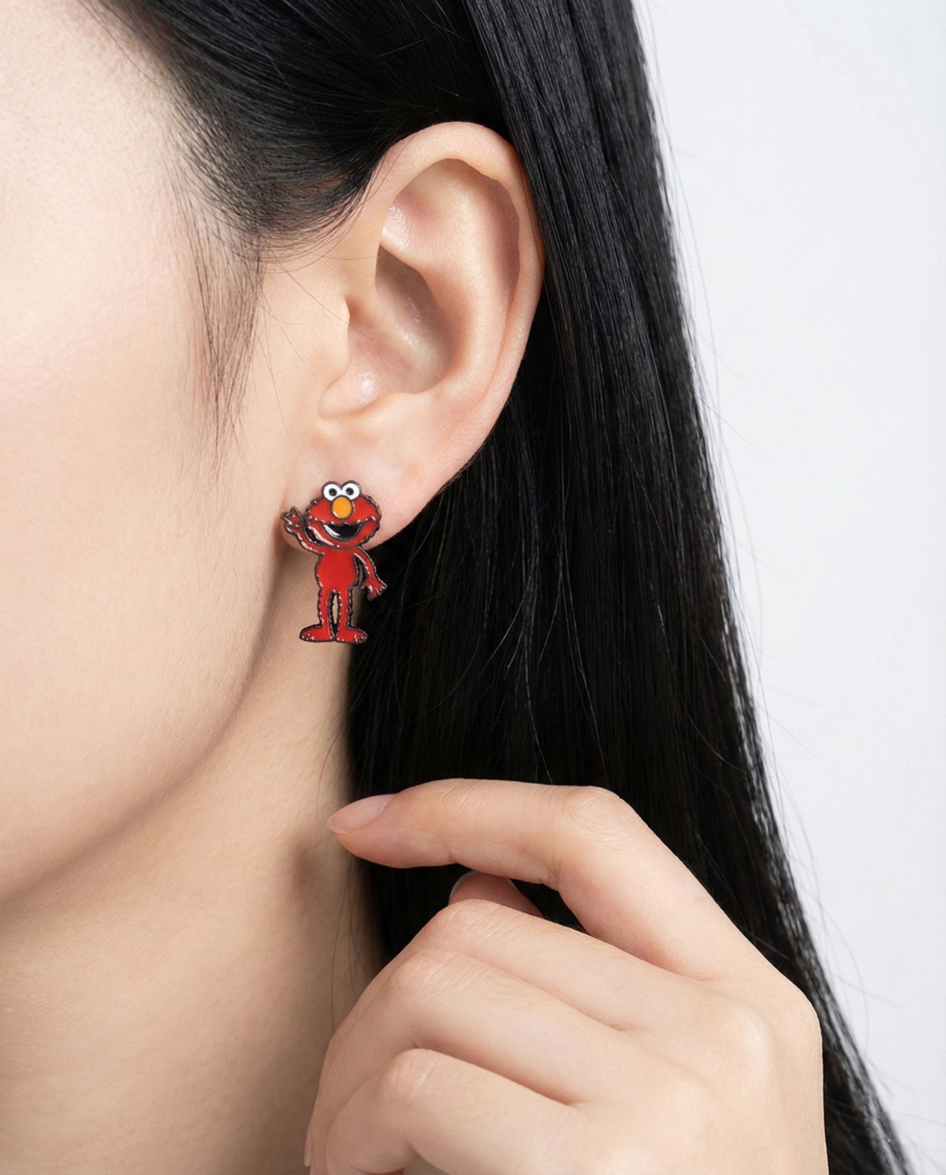 Elmo full-body earring styled alone on lobe, playful red tone pops against skin.