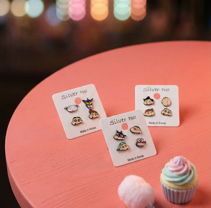 Crayon Shin-chan earring collection displayed on pastel table with cupcakes, kawaii aesthetic lifestyle shot
