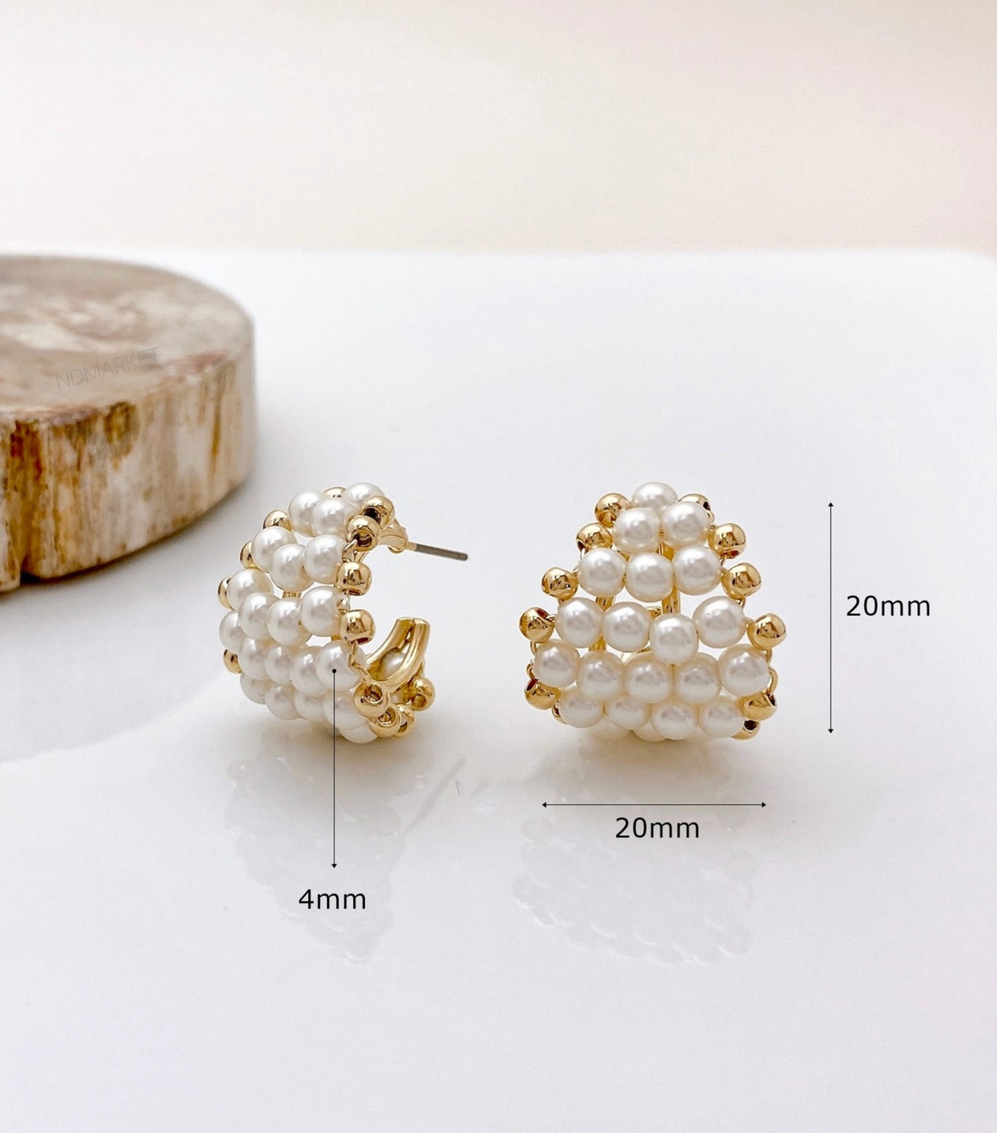 Size reference of pearl heart hoop earrings on wood - 20mm measurement shown