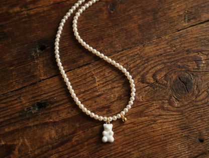 White pearl beaded necklace with gummy bear pendant on vintage wooden table